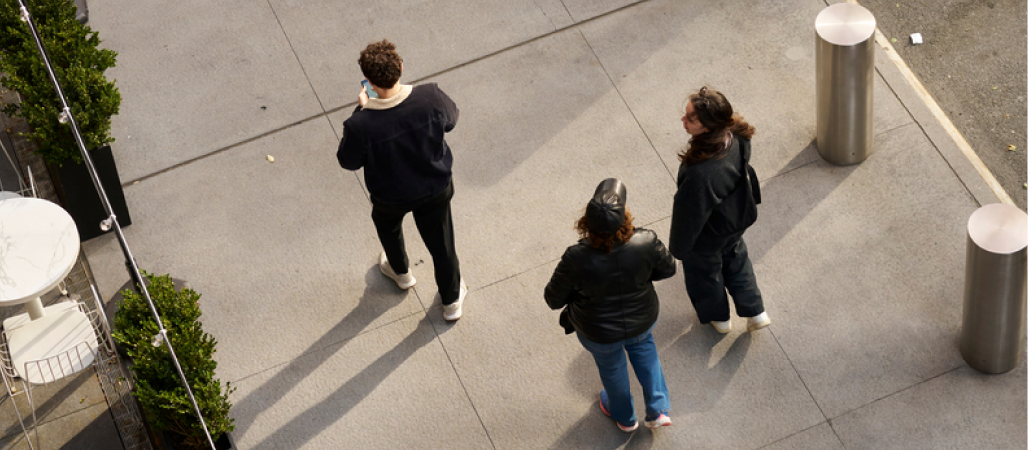 Image of a birds-eye-view of three people walking outside on a city side walk.