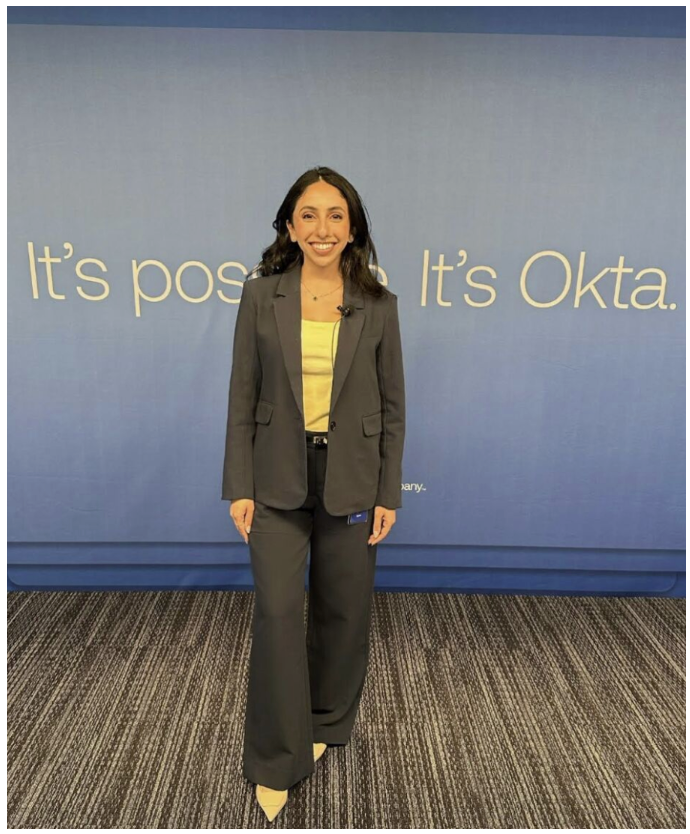 Sophia Jadallah standing and smiling in front of Okta catch phrase